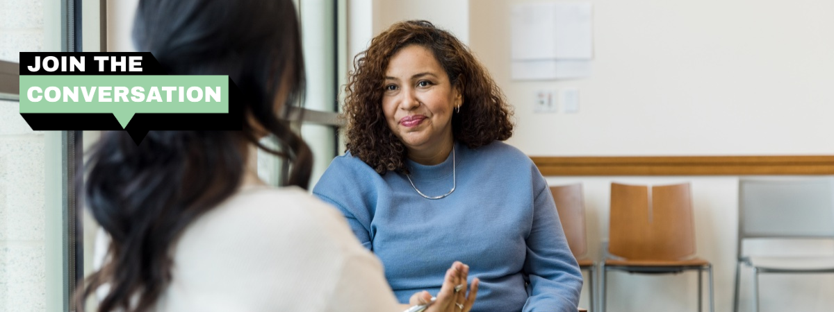 Two women chatting in an office with the words Join the conversation.